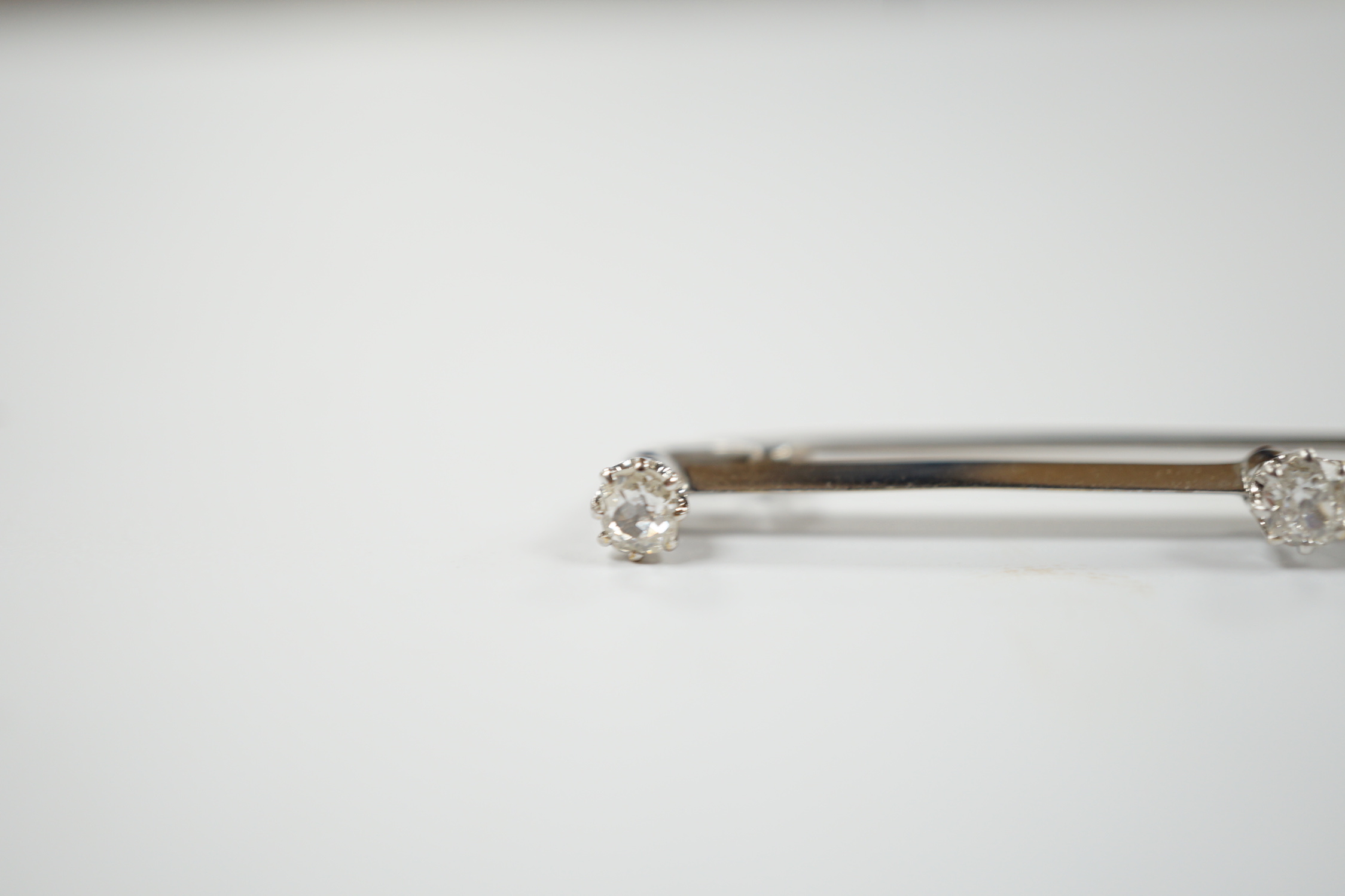 A white metal and three stone diamond set bar brooch, 56mm, gross weight 3.4 grams.